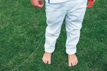 男孩正站在草地上.孩子的赤裸的双脚照片