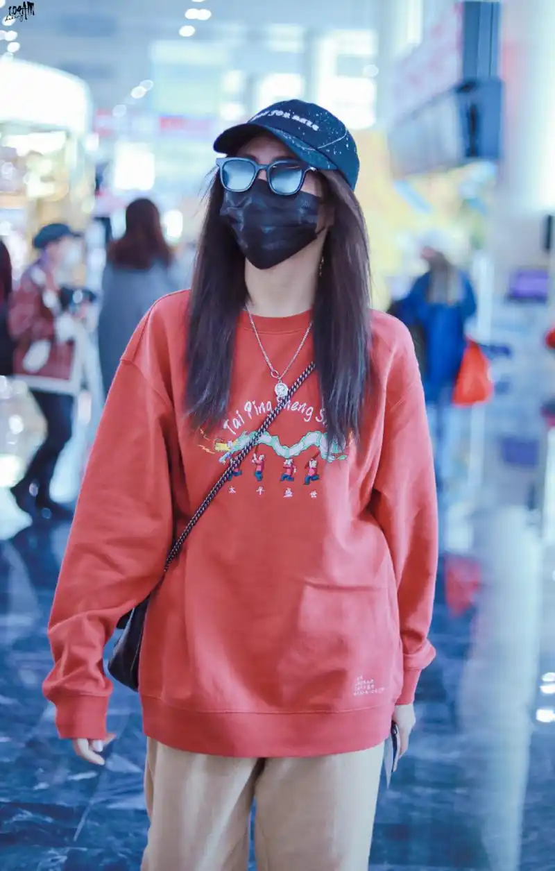 春运最in街拍#  谢可寅机场街拍,身穿橘色印花卫衣搭配米色直筒裤,斜