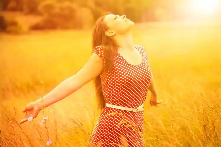 年轻快乐的女性在小麦田间享受金色的阳光