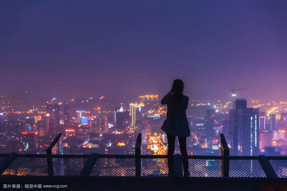 站在屋顶俯瞰城市夜景呼喊的女性全身背影