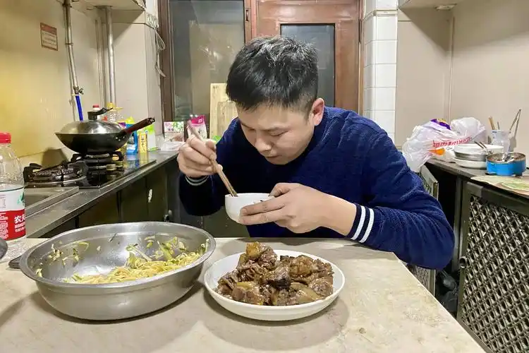 2月15日,在哈尔滨市香坊区租住的房子里,刘刚在吃饭(手机照片).