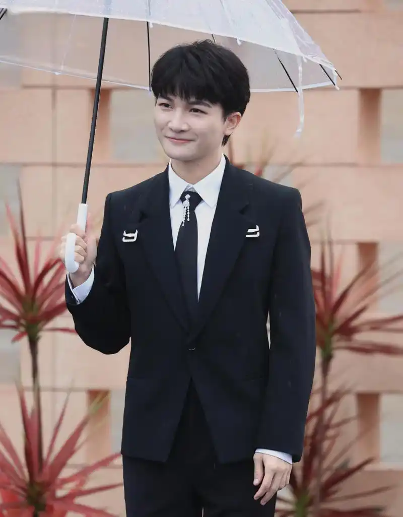 周深修伞,贴心敬业 歌手周深在红地毯上修伞的举动,展现了他的贴心与