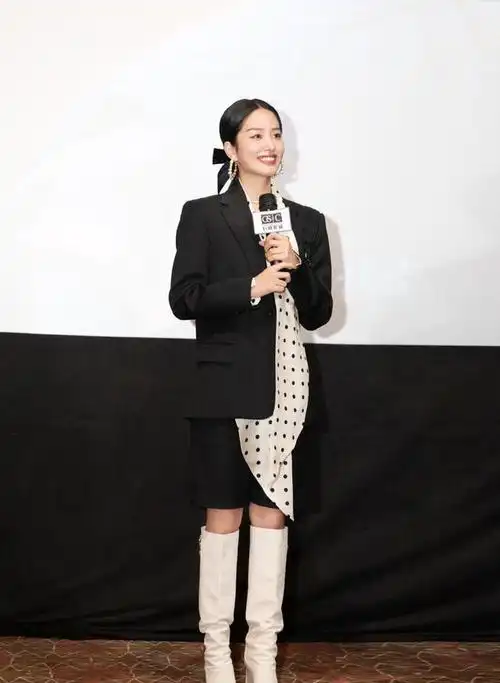 下半身的杨采钰穿着黑色的短裤,配合上面浅色的长靴,修长笔直的美腿和