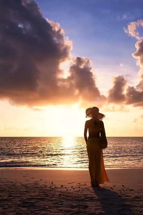 美丽的年轻女子在热带海滩上欣赏日落图片下载