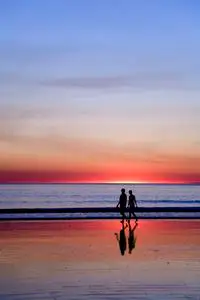 日落时分漫步在浪漫海滩上的年轻夫妇照片