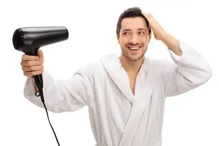 吹风机吹干吹干头发用吹风机浴袍的男人照片