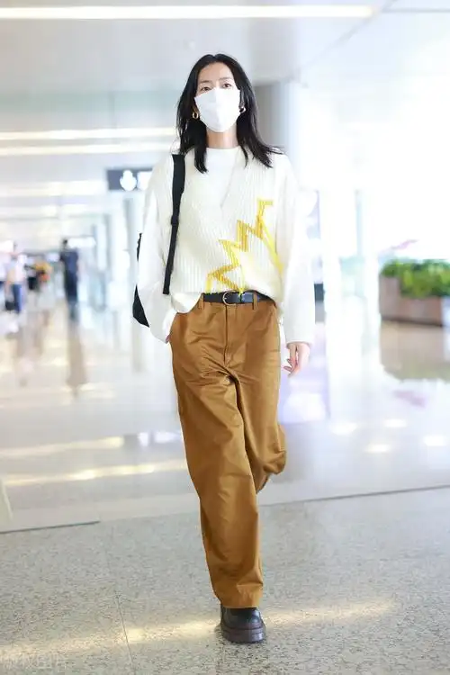 刘雯穿白色针织衫,搭配卡其色裤子,挥手打招呼尽显个人气质