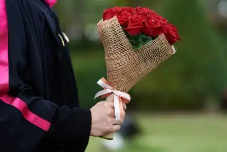 大学毕业生男一位身穿黑色长袍的年轻男毕业生捧着一束美丽的玫瑰花束