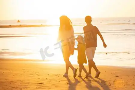 夕阳下一家三口在海边玩耍