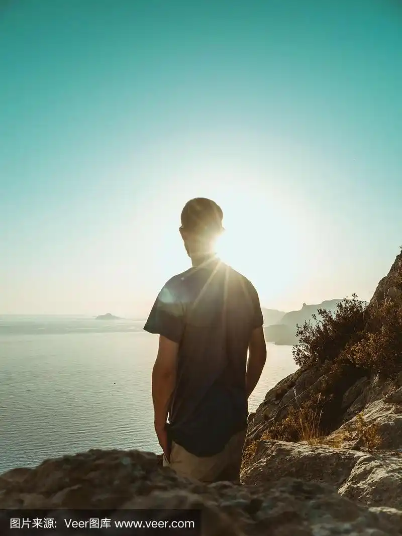 一个年轻人站在悬崖上,望着大海