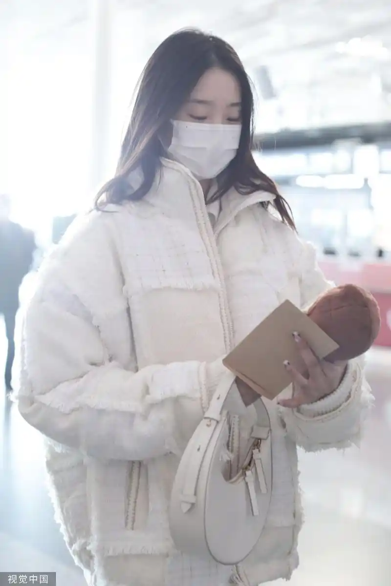 组图:张艺凡白色拼接棉服现身机场 手拿棉花娃娃笑容甜美