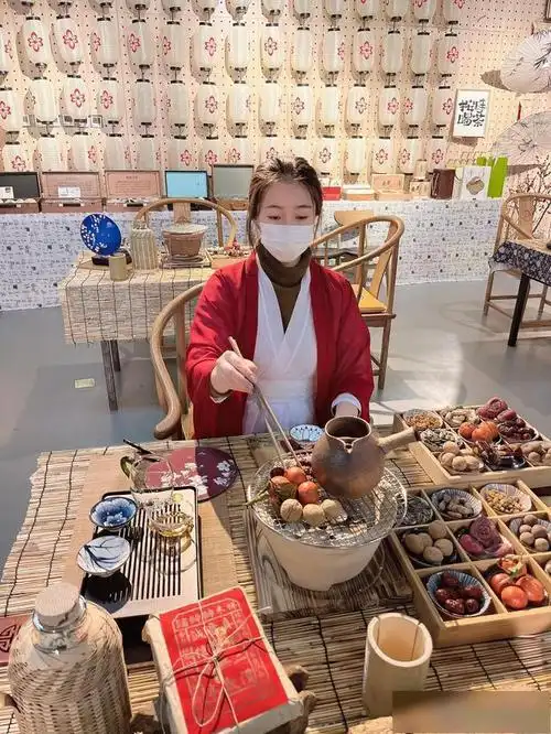 几个年轻人围炉而坐,炉子上煮着一壶热茶,配上柿子,橘子,花生,板栗