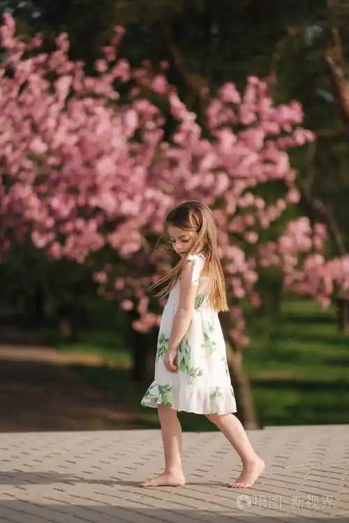 快乐的女孩儿赤脚走在公园里背景是粉红色的樱花树检疫结束可爱的小