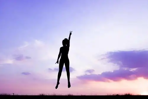 朝霞下跳跃的运动女生背影剪影