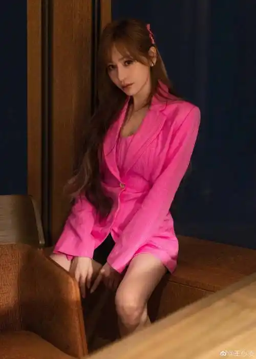 王心凌身穿粉色西装,她俏脸明媚,染黄的齐腰长卷发