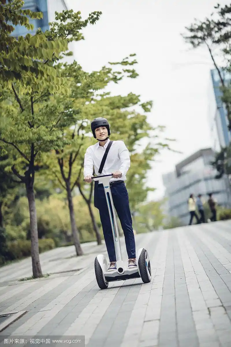 男人戴着头盔在街上骑电动车的照片