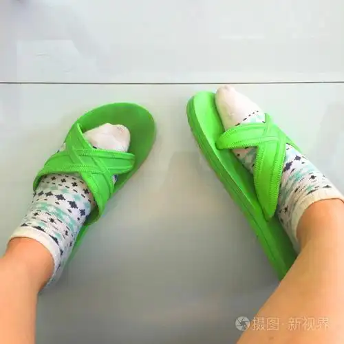 自拍照脚穿着白色圆点袜子和绿色拖鞋白色地板背景