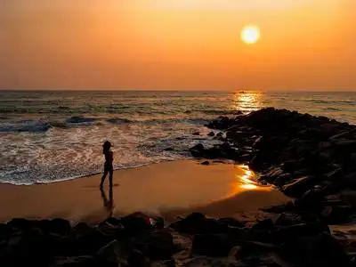 女孩在日落时沿着海滩散步照片