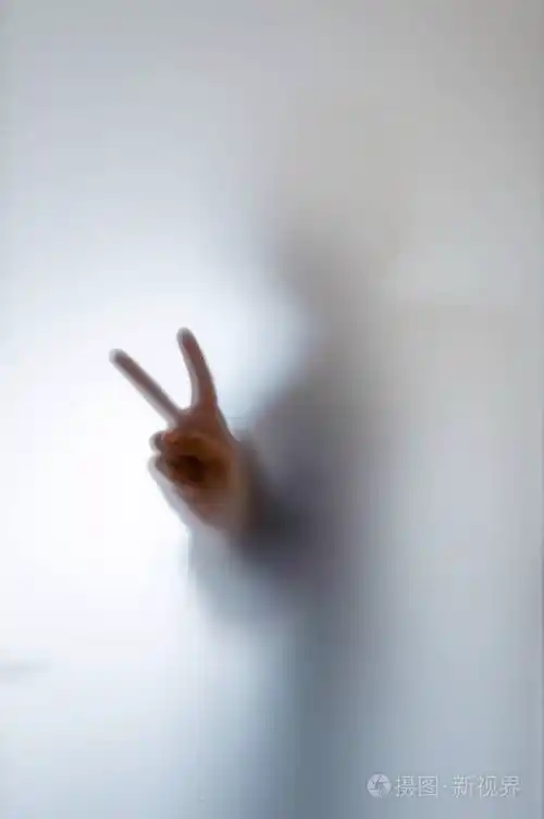 一个人在磨砂玻璃后面做和平标志的模糊身影