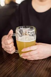 一个女人拿着一大杯淡冷的啤酒.与朋友见面照片