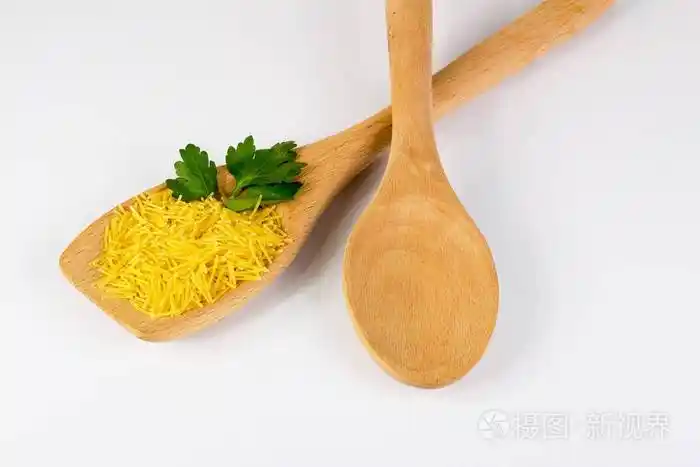 白色背景的木勺上放着欧芹的生粉丝