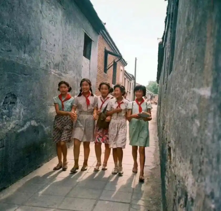 二十世纪八十年代,放学后,在胡同里结伴回家的女学生,她们穿着裙子,戴