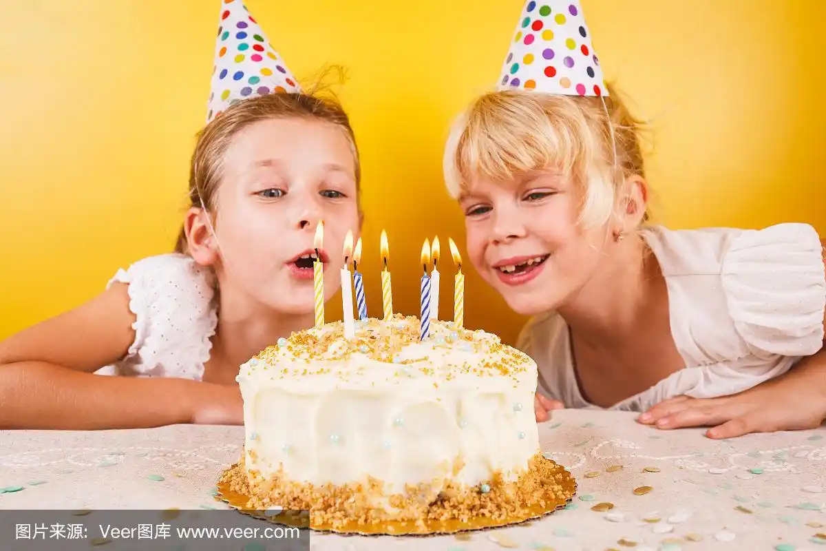 女孩们在吹生日蛋糕上的蜡烛.生日聚会庆祝概念.