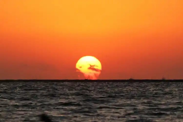 这轮日出就像巨大的太阳喷着天火,带着海水蒸腾着冲出海平面.