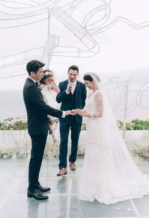 在婚宴主持人的讲演下,穿着白色蕾丝露背婚纱的贾静雯,与黑色正装的