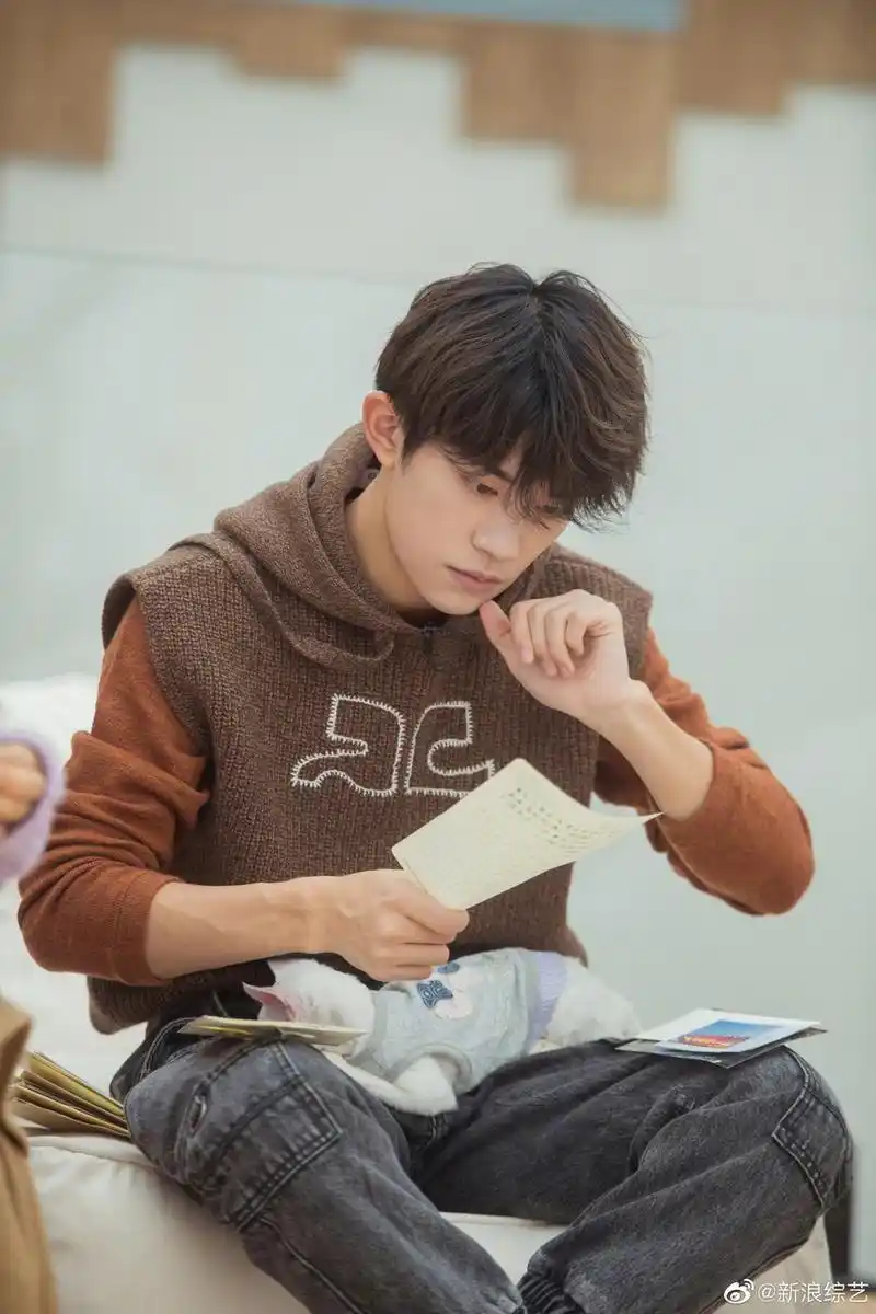 易烊千玺穿复古连帽马甲专注聆听梨涡浅笑文艺范十足