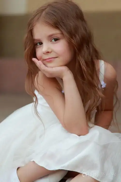 肖像的可爱微笑的小女孩,长头发的漂亮的衣服坐在户外的步骤