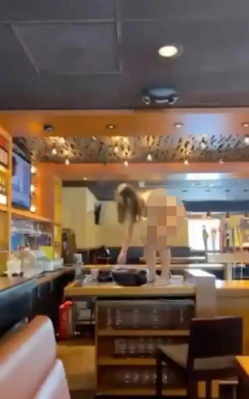 美国女子光着全身闯进餐厅到处撒野乱扔酒瓶被警方击中胸部倒地