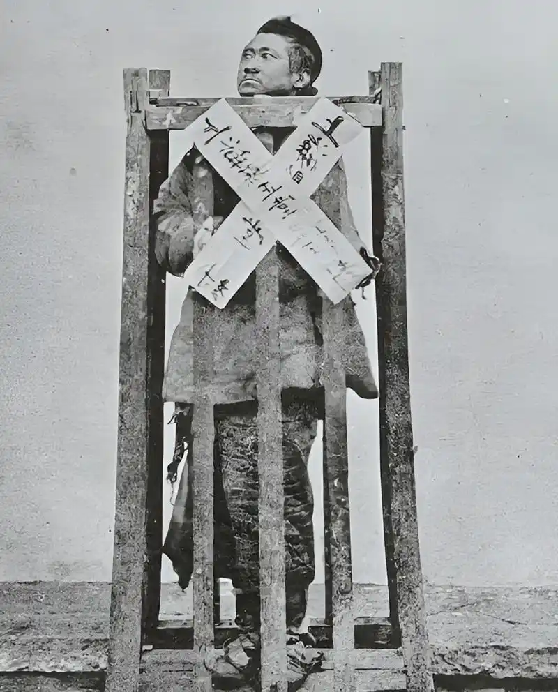 一个满族人被关在笼子里,他双手插在袖子里,眼神充满无助和绝望.