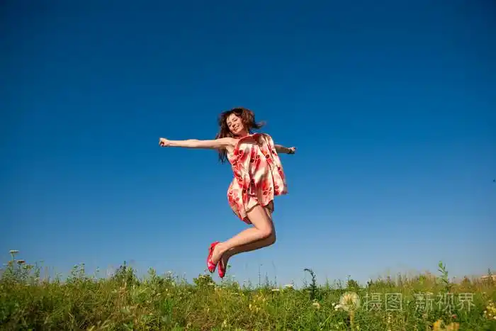 快乐的年轻女子在田间跳跃