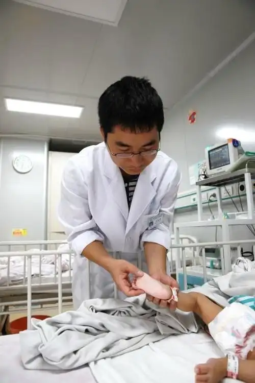 副主任医师,清远市人民医院儿科专家戴汝均为手足口病患儿检查身体