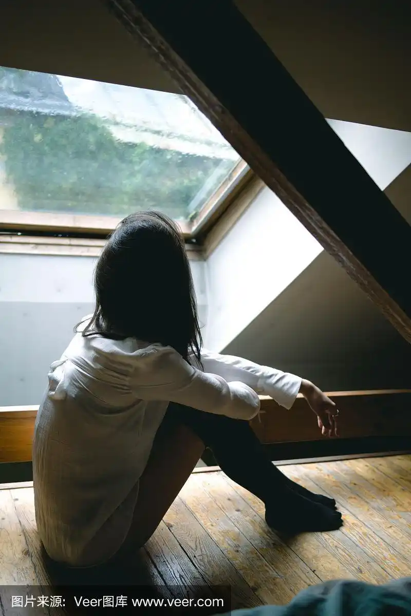 年轻悲伤的女孩坐在她卧室的地板上