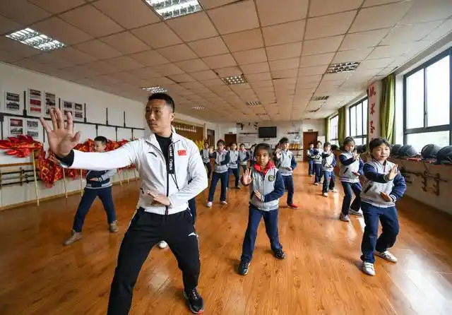 迎宾路小学的体育教师曾科(前)在教授二年级学生五行拳法(3月10日摄).