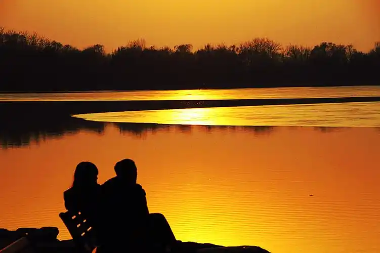 《赏夕阳》一对恋人坐在湖边的条椅上,尽情的观看美丽的晚霞.