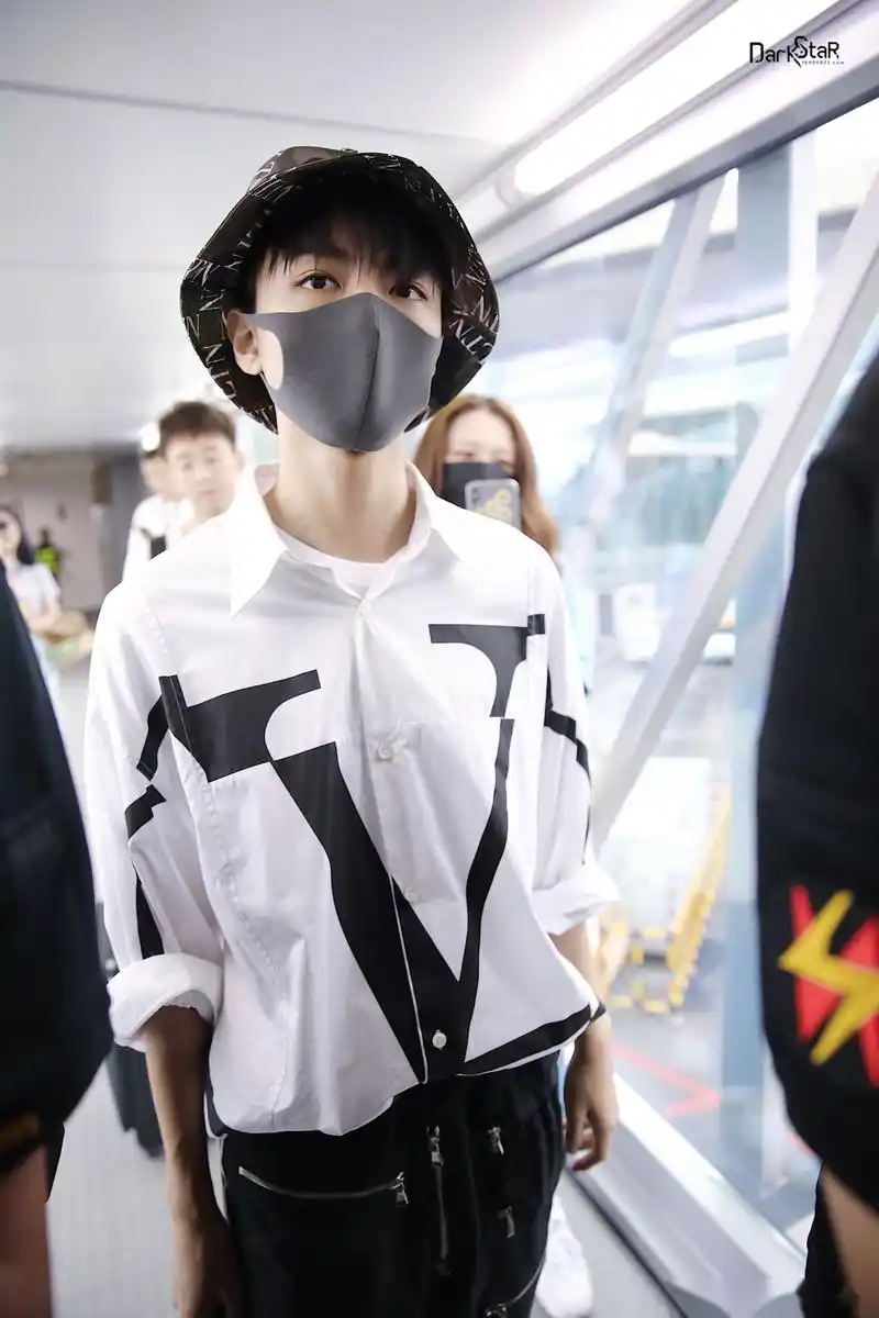 王俊凯重庆机场北京 迷彩渔夫帽男孩清爽出镜,身穿大写v字的白色衬衫