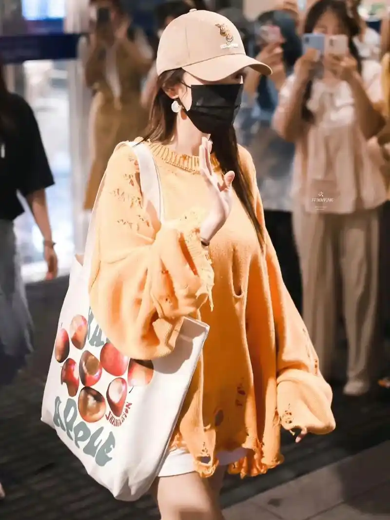 女星杨幂近日一则机场私服穿搭分享,橙色破洞针织衫搭配运动鞋,下身