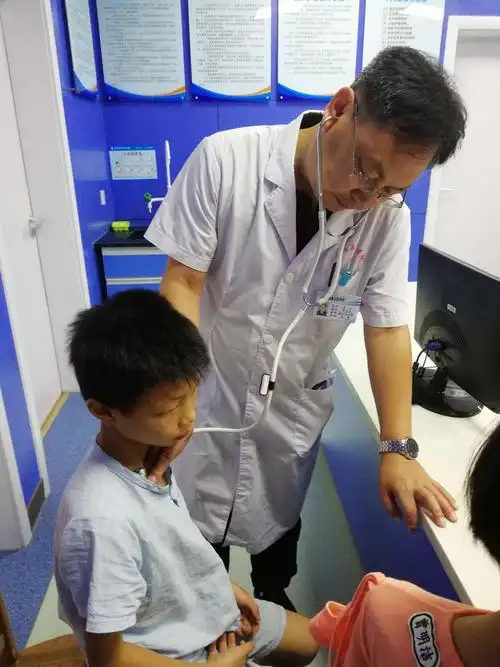 县人民医院儿科主任覃云医师正在为儿童患者检查