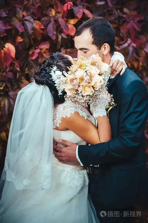照片 接吻的结婚礼服的年轻夫妇.新娘控股束鲜花.jpg