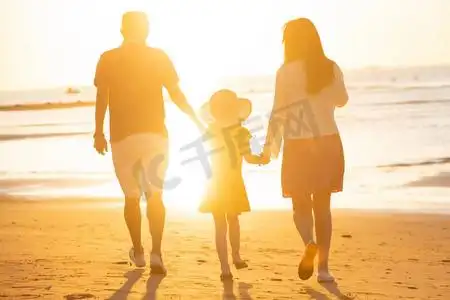 夕阳下一家三口在海边玩耍
