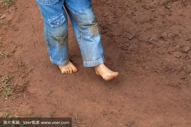孩子肮脏的脚在泥泞的地面上