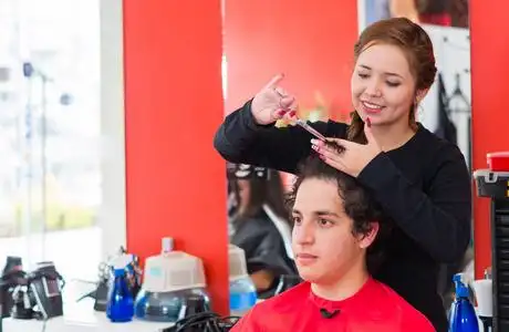 在理发店里,一位年轻漂亮的发型师正在剪发照片