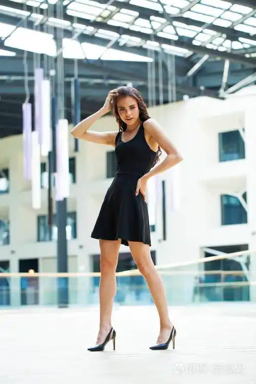 一个穿着黑色衣服的快乐的年轻黑发女人的全身肖像