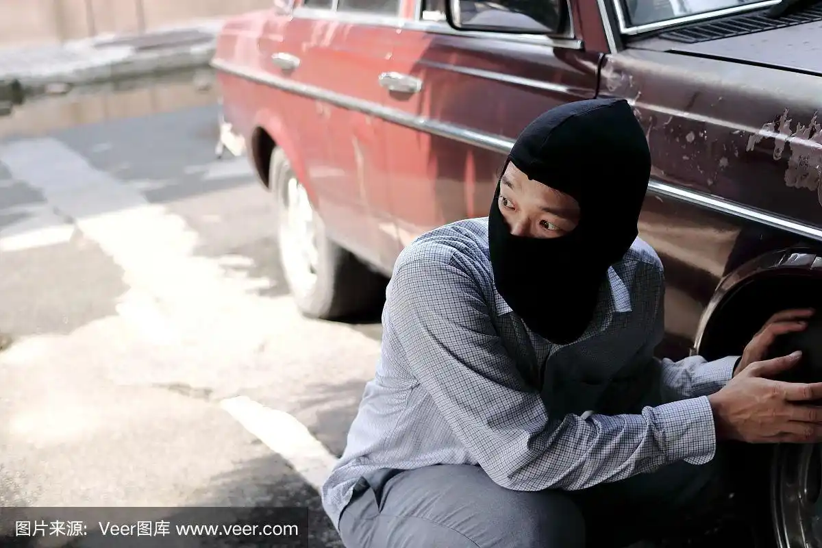 戴着黑色巴拉克拉瓦帽的蒙面小偷试图闯入汽车.刑事犯罪的概念.