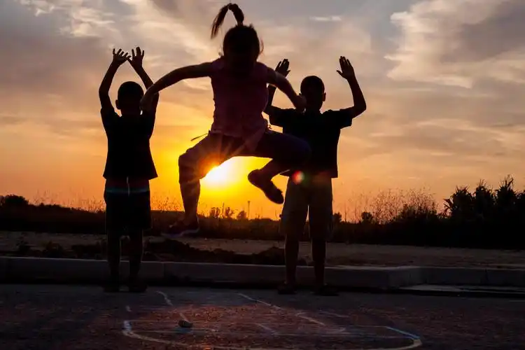 年轻的男孩和小女孩在夕阳下玩耍的剪影