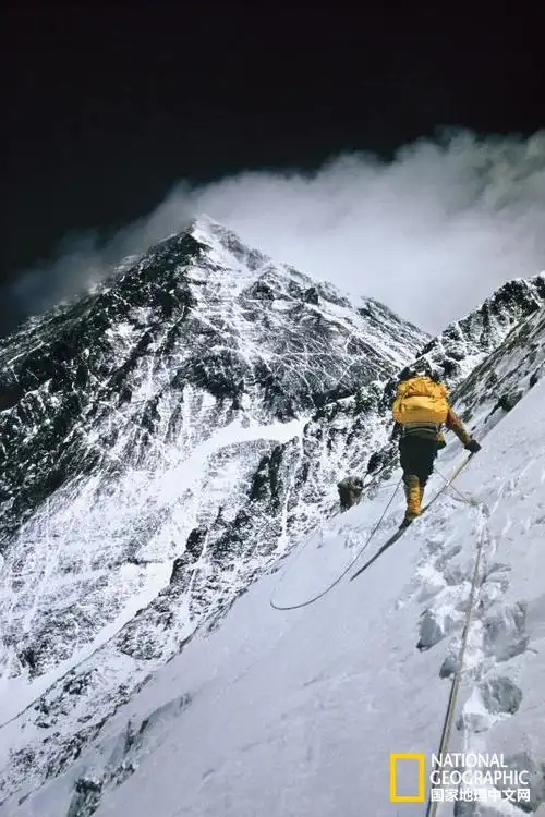 这张老照片里,一位登山者在珠峰攀登途中从岩壁一侧横切向上.