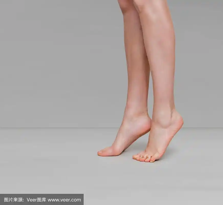 在浅灰色的背景上,女性纤细的腿踮起脚尖